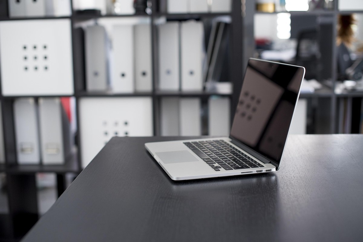 Laptop ouvert sur bureaux moderne avec étagères de rangement en arrière-plan
