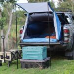 Camper-tente sur coffre d'un SUV, camping en bord de lac, objets de rangement, chariot à bagages