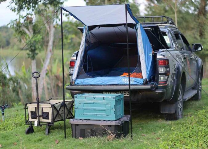 Camper-tente sur coffre d'un SUV, camping en bord de lac, objets de rangement, chariot à bagages