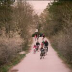 Cyclistes sur un chemin de terre, en pleine nature, entourés d'arbres et de buissons