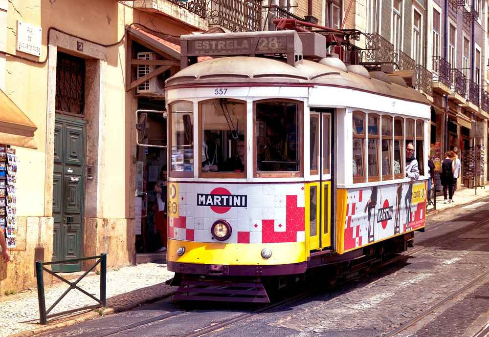Un tramway ancien coloré circule dans une rue pavée animée