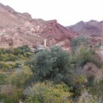 Un village traditionnel niché entre montagnes rouges et verdure luxuriante