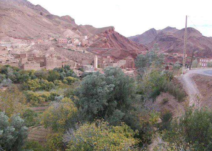 Un village traditionnel niché entre montagnes rouges et verdure luxuriante