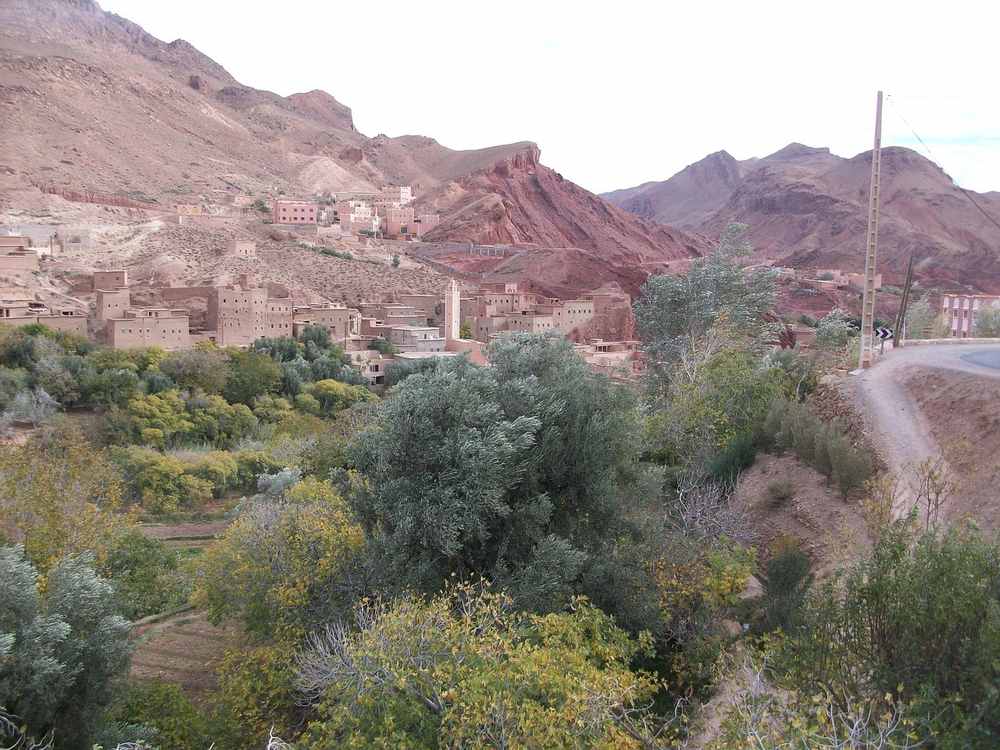 Un village traditionnel niché entre montagnes rouges et verdure luxuriante